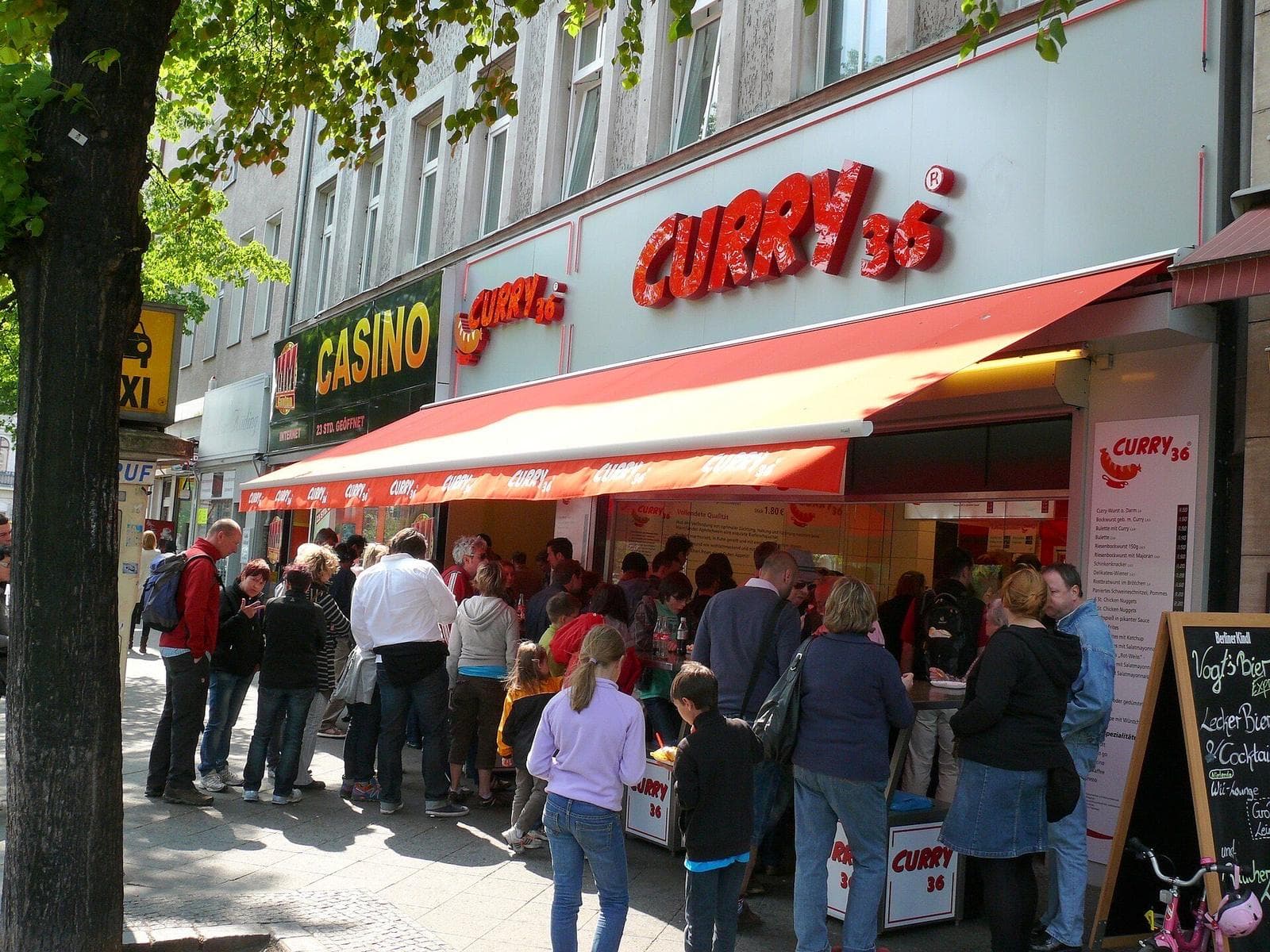 Wachtende klanten bij de rood-witte snackbar Curry 36 aan de Mehringdamm in Kreuzberg