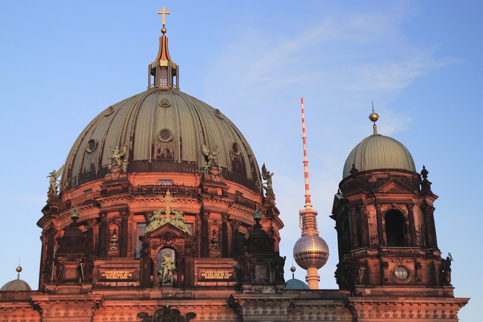 De koepel van de Berliner Dom in warm avondlicht, met de Fernsehturm op de achtergrond