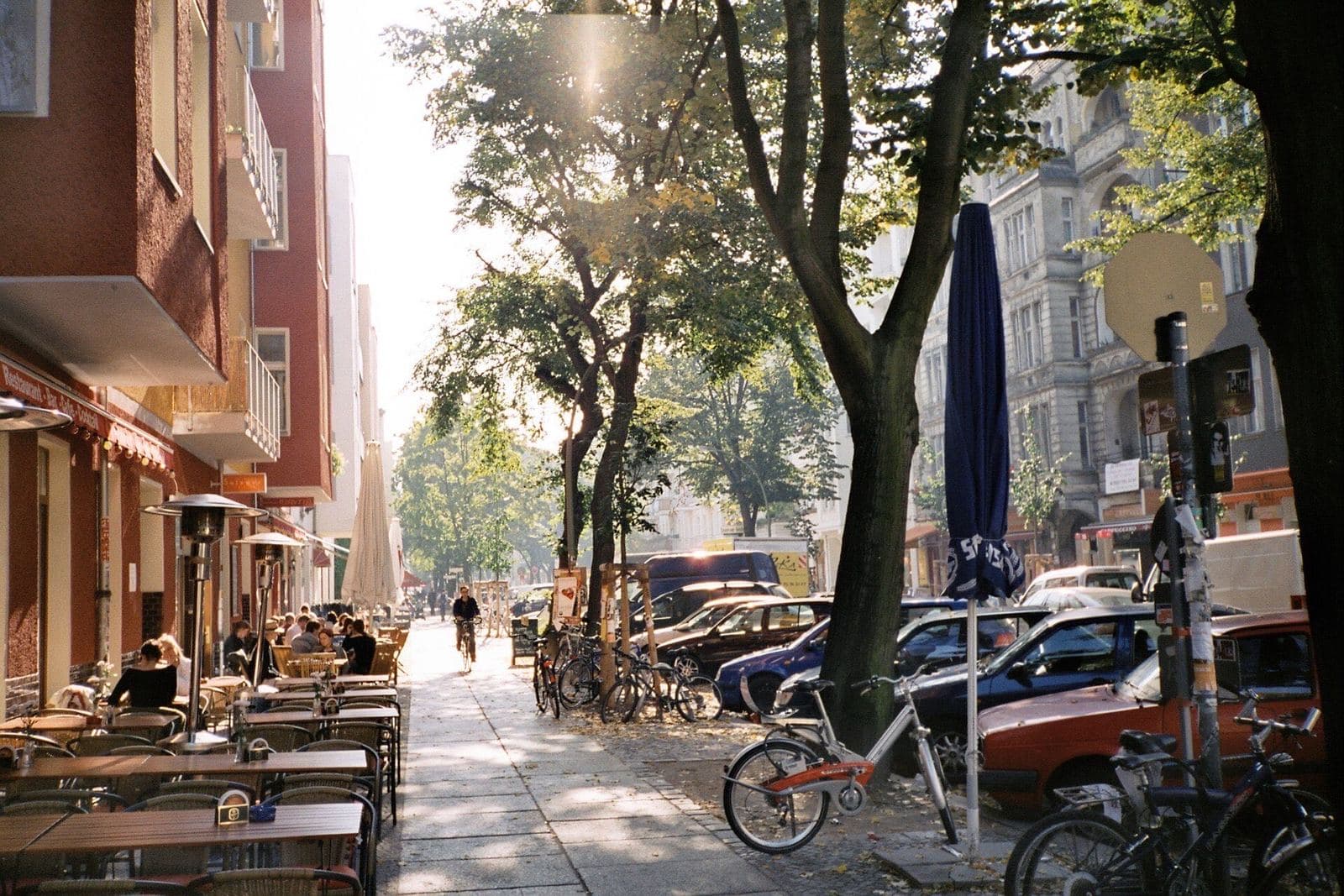 Terrassen en fietsen onder de bomen van de Simon-Dach-Straße in Friedrichshain