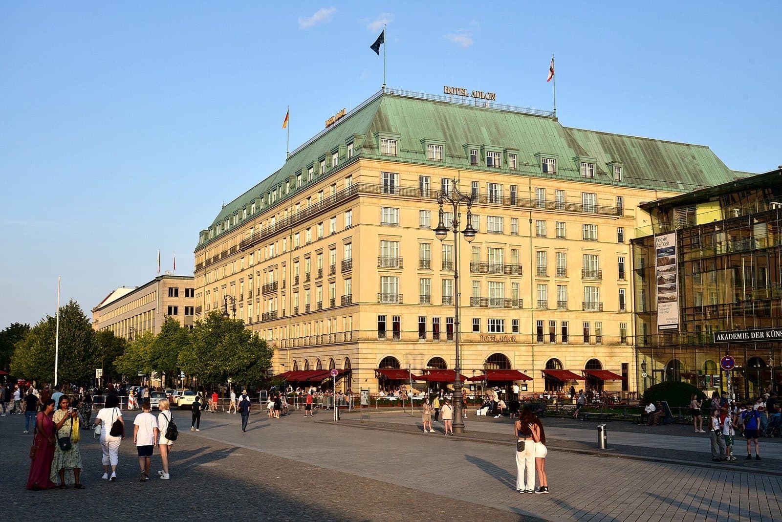Hotel Adlon Kempinski aan de Pariser Platz in avondzon, met wandelaars op het plein
