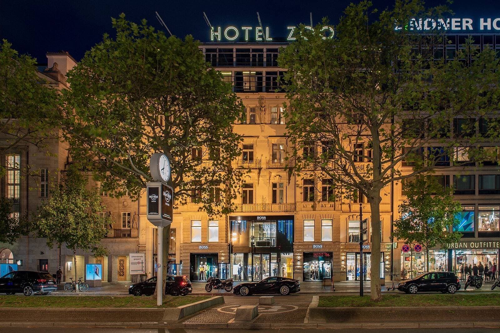 De verlichte gevel van Hotel Zoo aan de Kurfürstendamm, 's avonds tussen de bomen