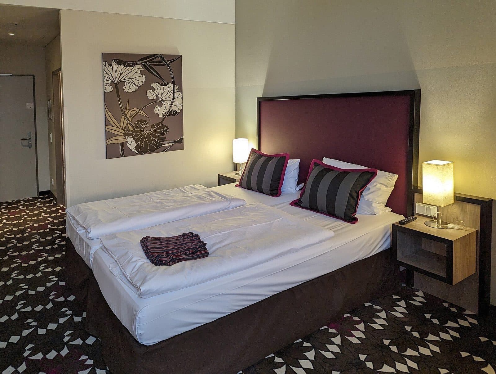 Een lichte tweepersoonskamer in een Berlijns hotel, met leeslampjes en een gedessineerd tapijt