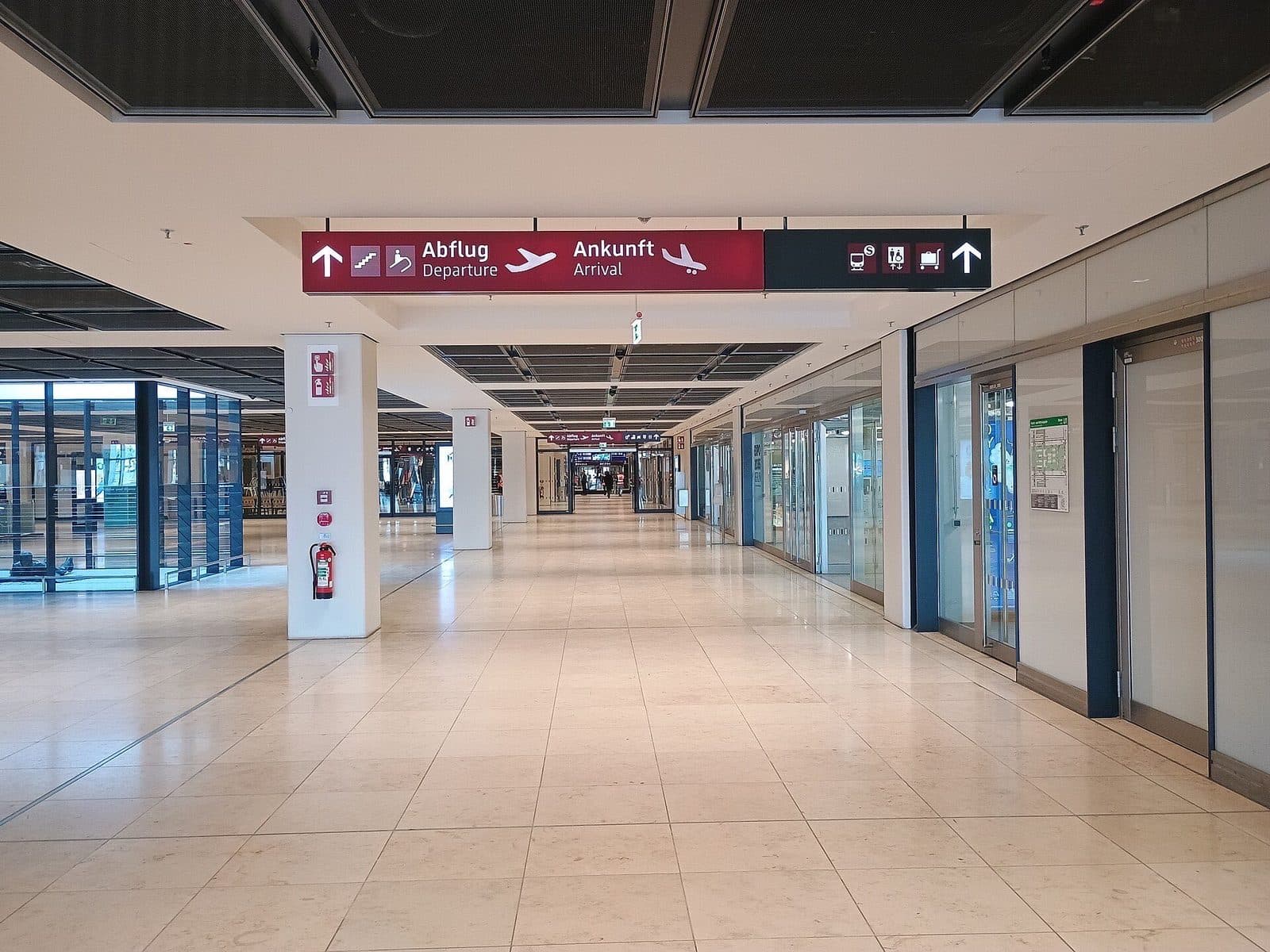 Lichte, ruime hal in Terminal 1 van luchthaven BER met borden naar vertrek en aankomst