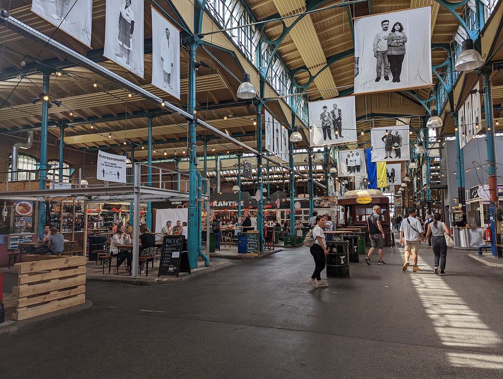 Het interieur van Markthalle Neun in Kreuzberg met ijzeren spanten, marktkramen en hangende portretten