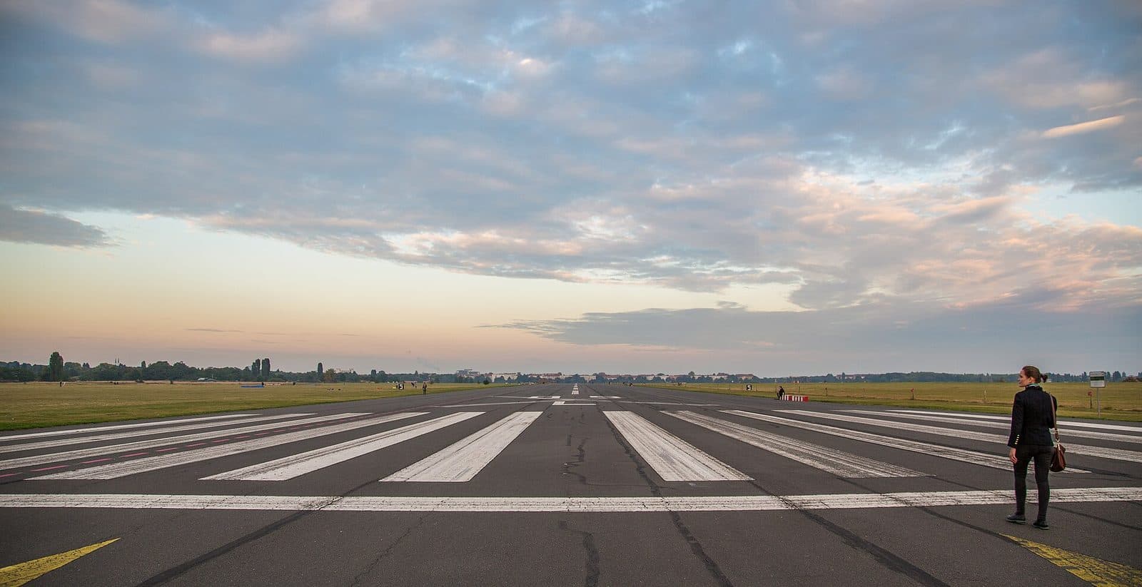 De oude start- en landingsbaan van Tempelhofer Feld bij zonsondergang, met een wandelaar op de baan